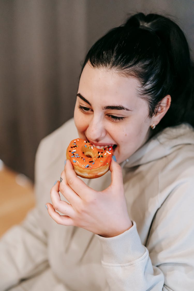 Happy Young Woman Eating Tasty Donut