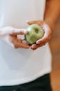 Crop unrecognizable person demonstrating green apple