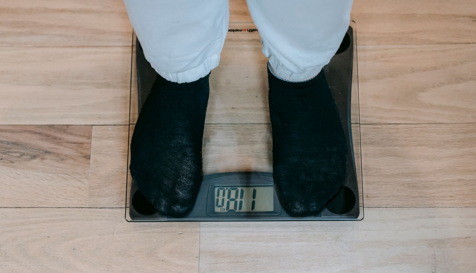 Person using a digital bathroom scale during a home health monitoring routine