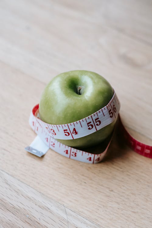 Free Green apple with measuring tape on table in kitchen Stock Photo