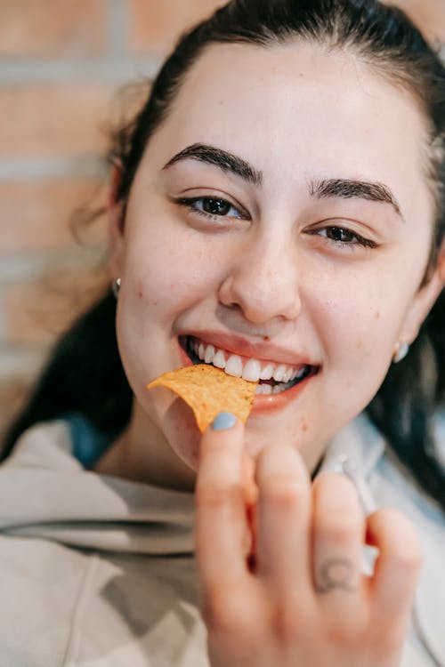 Free Smiling ethnic woman eating chips Stock Photo