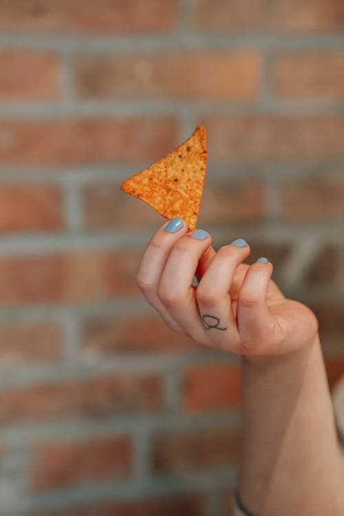 Crop woman with corn chip in hand