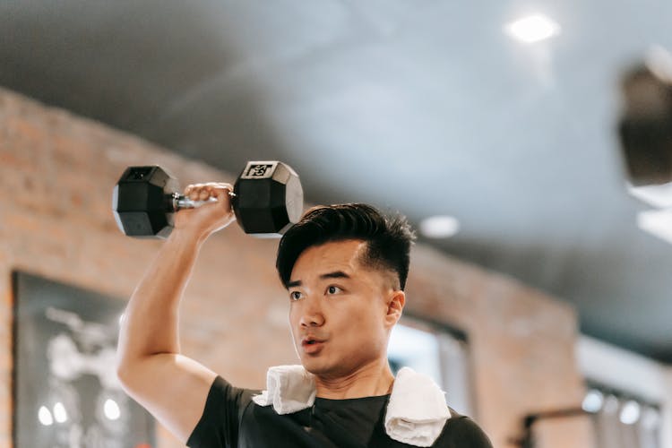 Muscular Asian Man Lifting Dumbbell In Gym