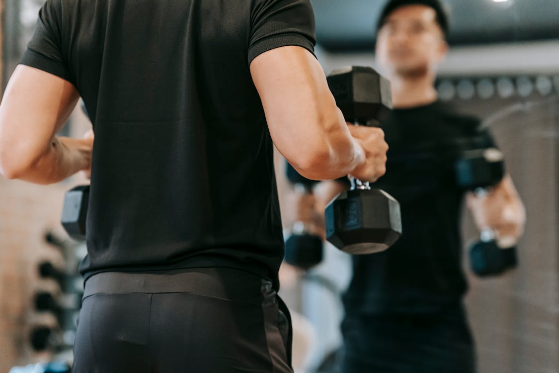 Free Crop sportsman with dumbbells in fitness studio Stock Photo