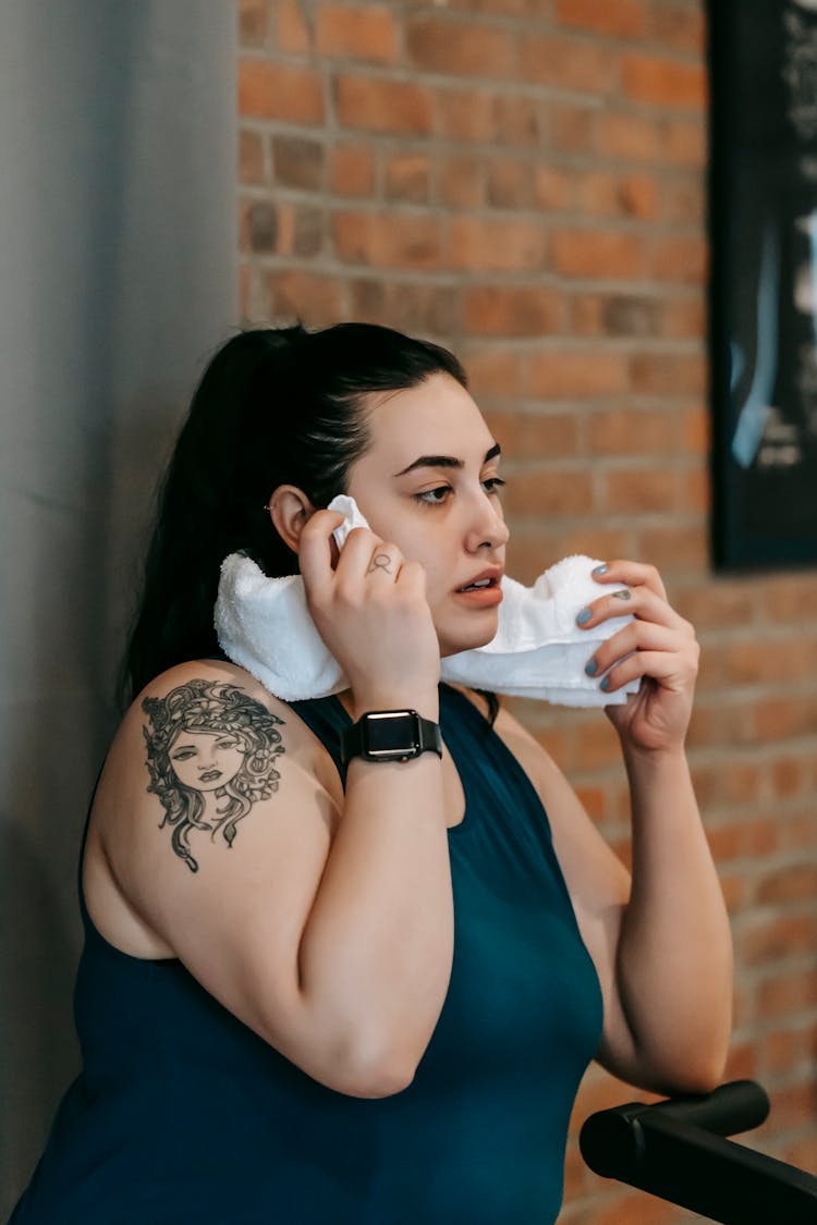 Tired Ethnic Overweight Woman Wiping Sweat From Face In Gym