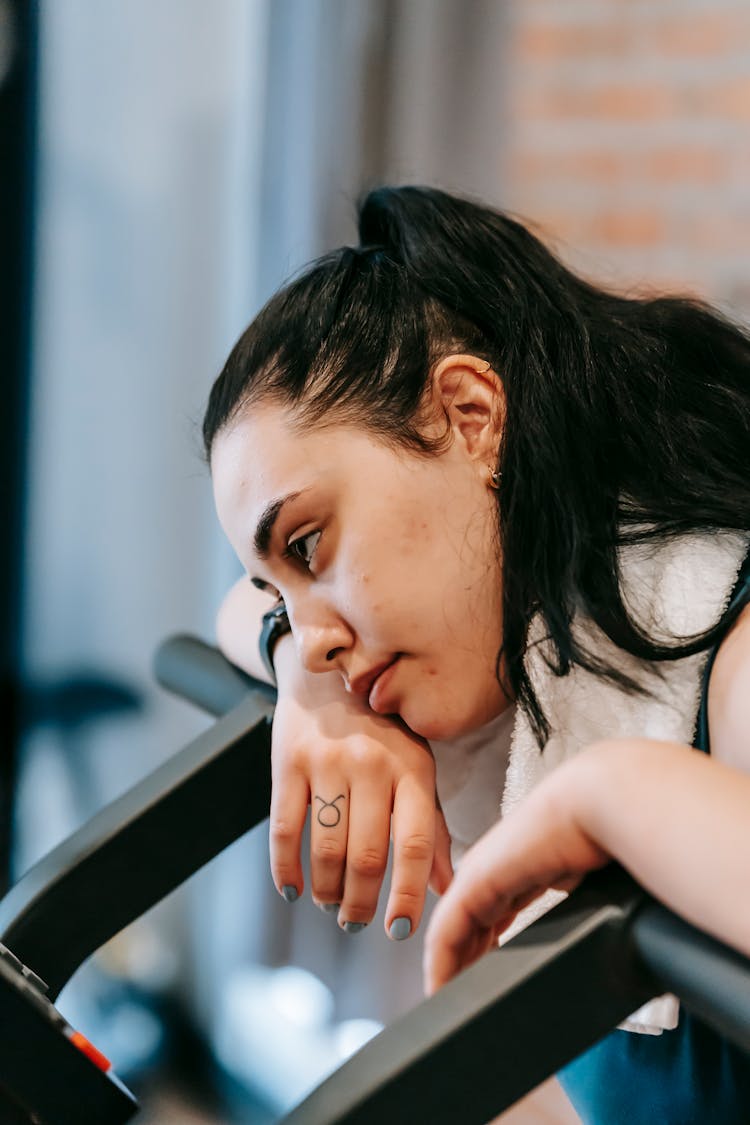 Tired Ethnic Woman Leaning On Exercise Machine