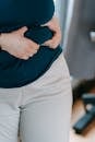 Crop anonymous plus size female touching belly on blurred background of gym in daytime