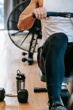 A focused adult male works out on a rowing machine in a modern gym setting.