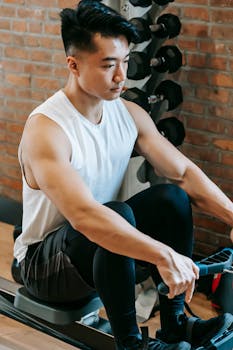 Young man in activewear working out on a rowing machine at a gym, demonstrating focus and fitness.
