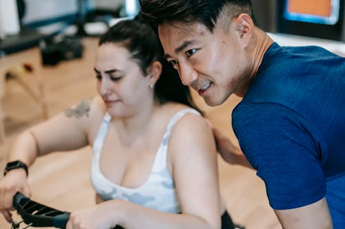 Young multiracial male trainer and overweight woman exercising in gym