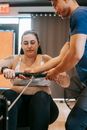 Asian male instructor helping overweight woman during intense workout