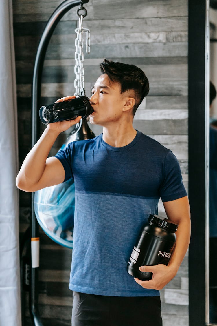 Asian Athlete Drinking Water Standing With Bottle Sports Supplements