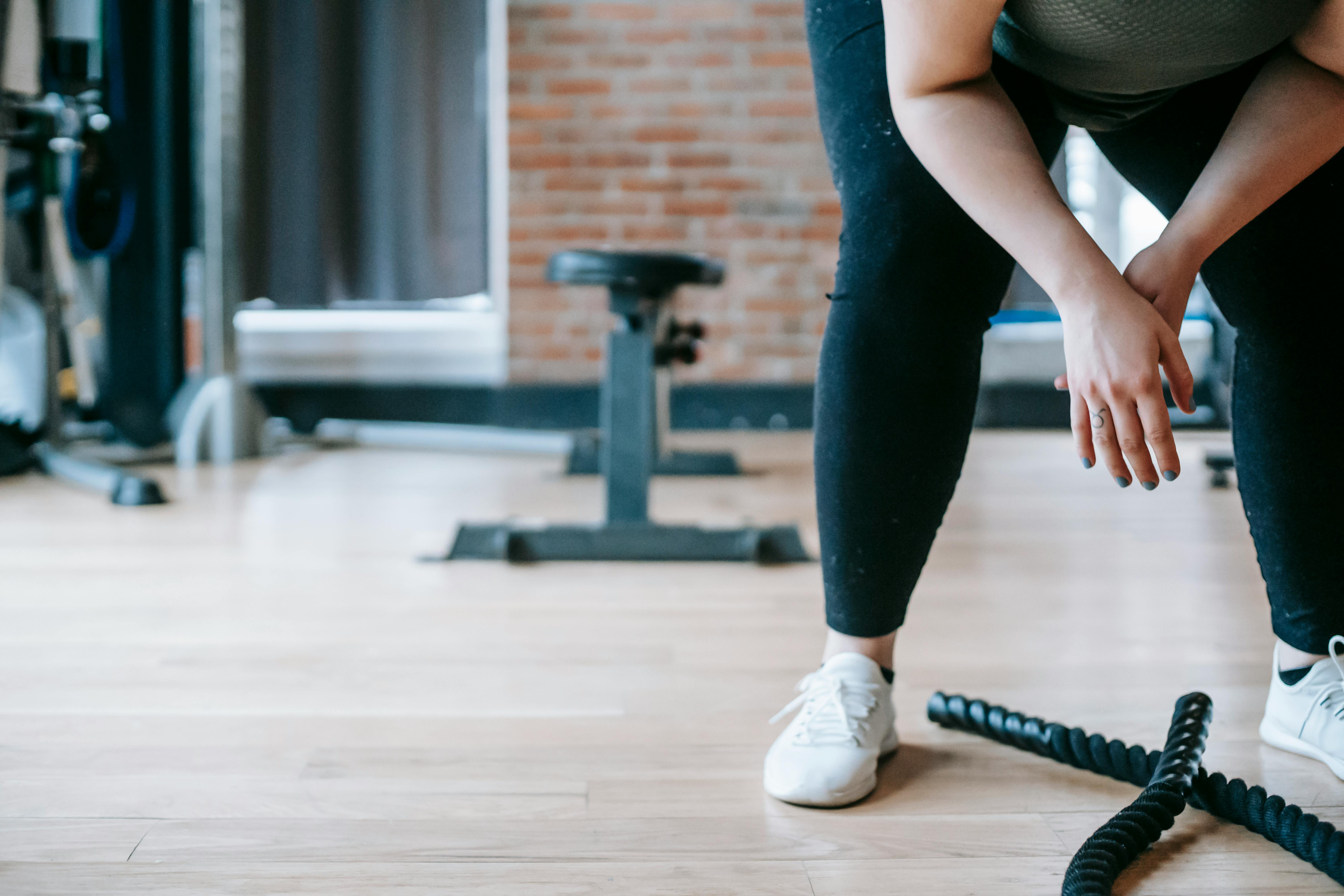 woman bending above battle ropes in gym