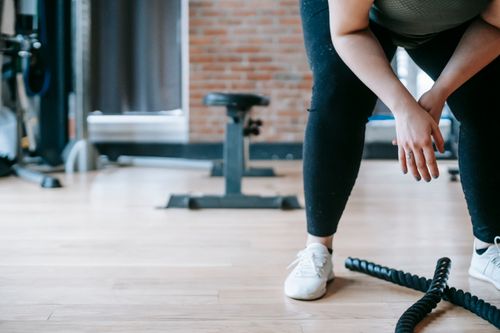 Free Crop anonymous female in sportswear resting after workout with ropes in gym with sports equipment Stock Photo