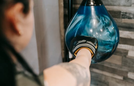 A focused woman punches a speed bag in a gym setting, showcasing strength and determination.