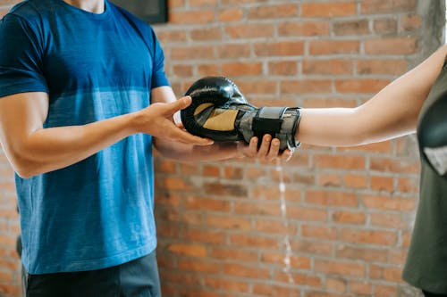 Free Personal trainer helping woman putting on gloves Stock Photo