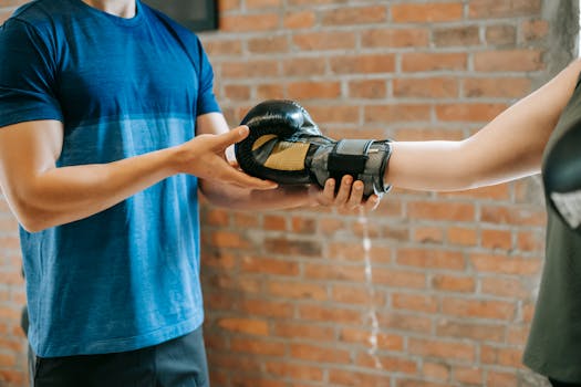 Trainer assisting client with boxing gloves in a gym setting.