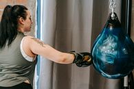 Female punching boxing ball during training in gym