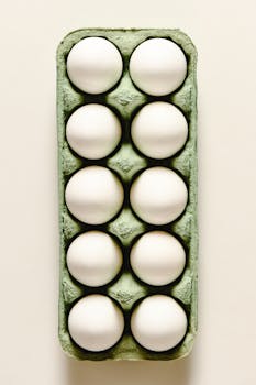 Top view of ten white eggs in a green carton with ample copy space.