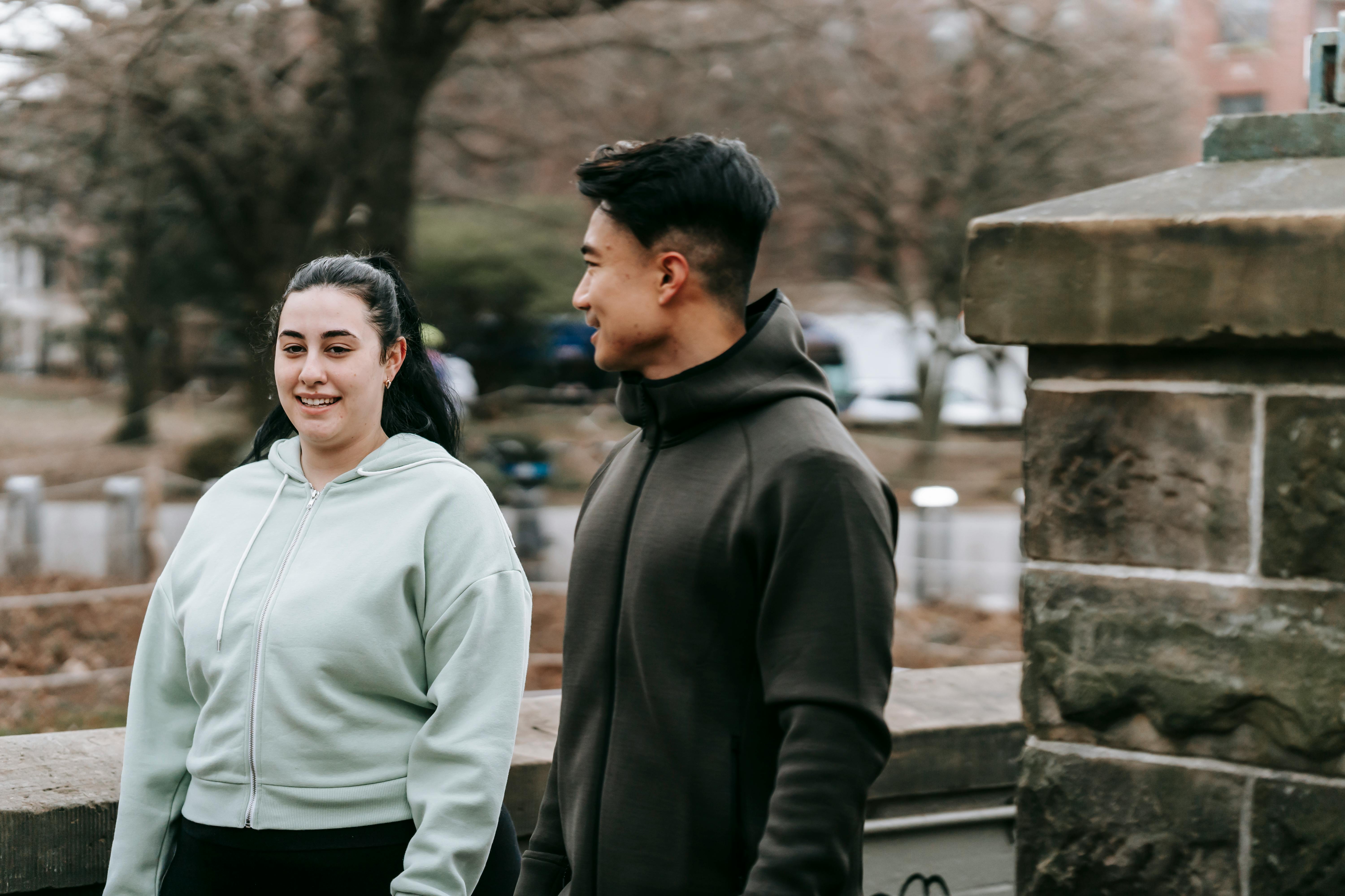 positive multiethnic friends chatting in park after workout