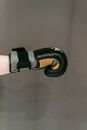 Side view of crop anonymous person in boxing gloves punching against gray background during workout