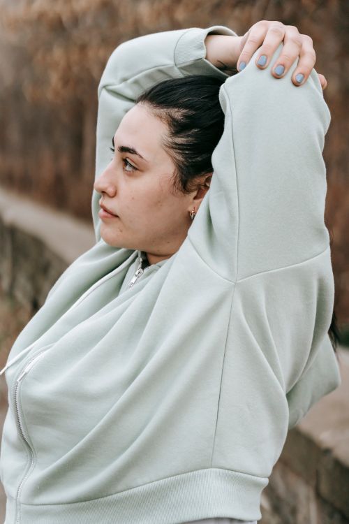 Free Side view of young overweight female looking away and stretching on blurred background of nature in daytime Stock Photo