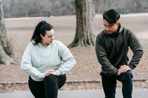 Free Plus sized woman training with Asian man in park Stock Photo