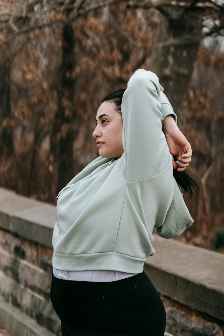 Plus Sized Woman Stretching In Autumn Park In Daylight