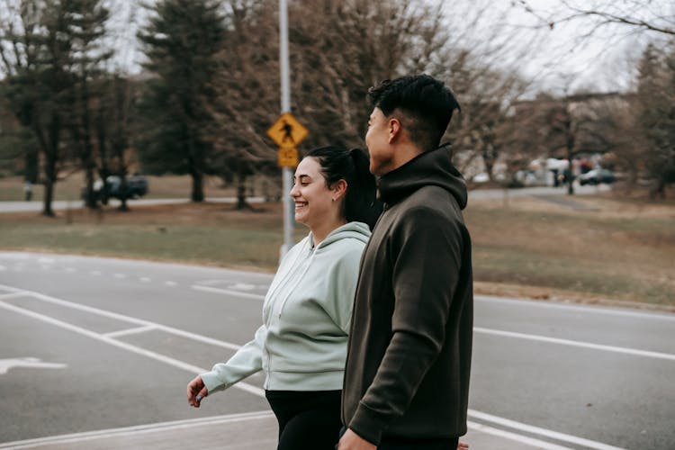 Positive Couple In Activewear Walking On Street Near Road