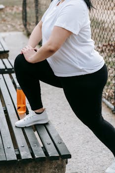 Unrecognizable woman stretching on a bench outdoors, epitome of a healthy lifestyle.