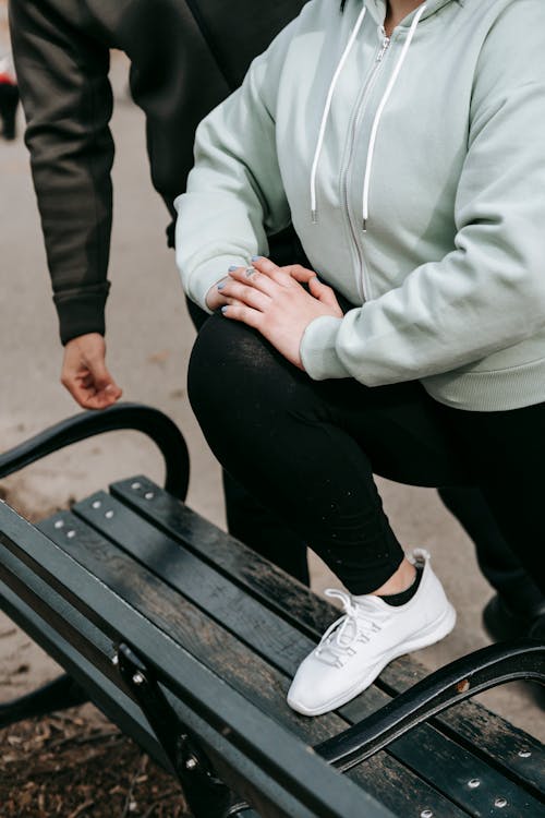 Anonymous woman warming up in park during workout with instructor