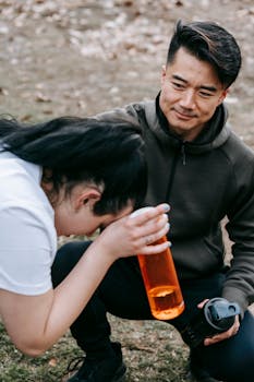 Asian trainer coaches young woman taking a break from exercise in park.
