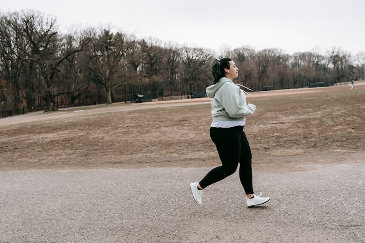 Plus Size Woman Running In Autumn Park