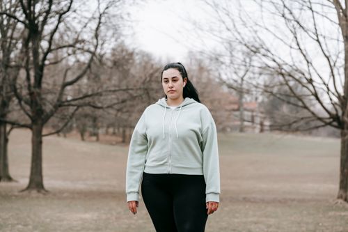 Free Young overweight female in activewear and earphones resting in autumn park on gloomy day Stock Photo