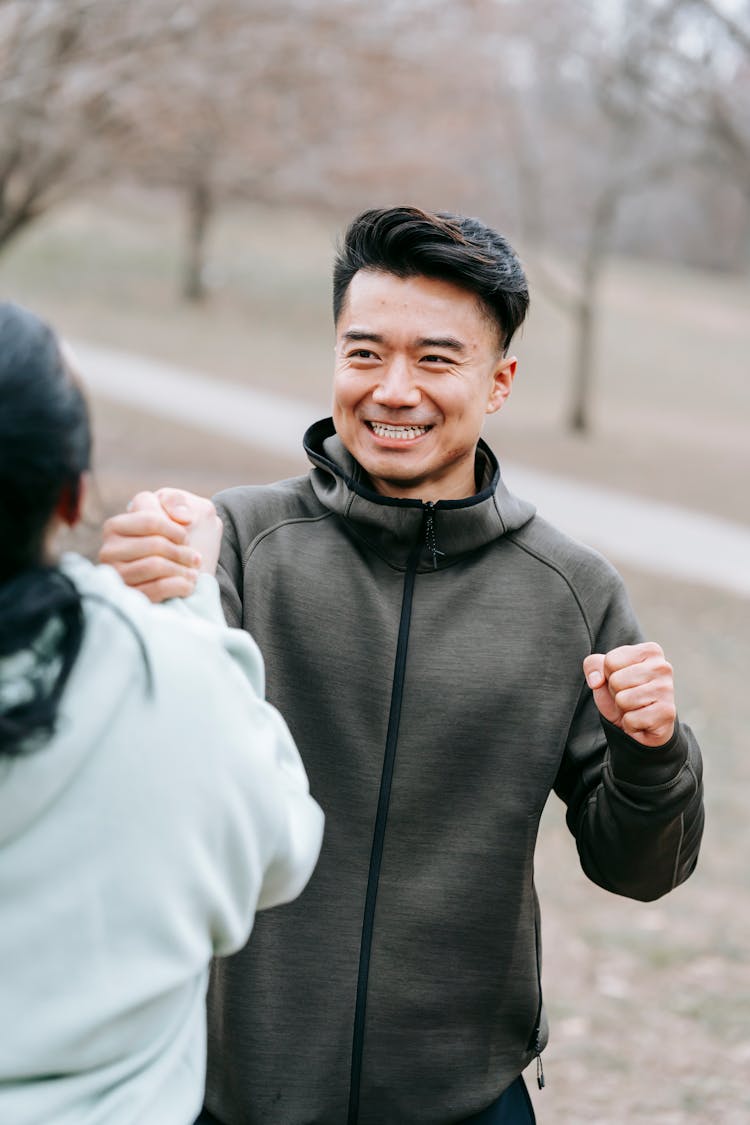 Happy Asian Man Holding Hand Of Woman In Park