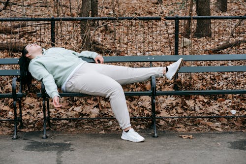 Free Tired Woman Lying on Bench in Park Stock Photo