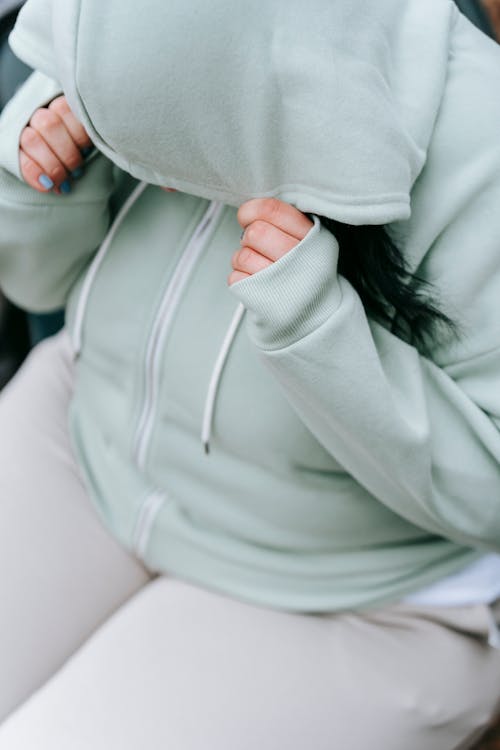Overweight woman in sportswear hiding face under hood