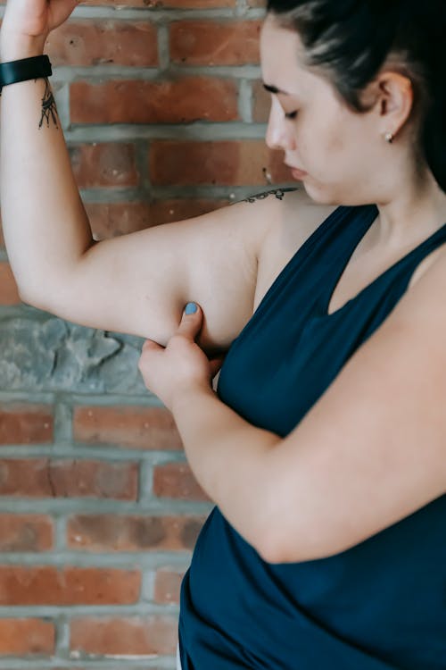 Free Unhappy plus size female showing excess fat on arms Stock Photo