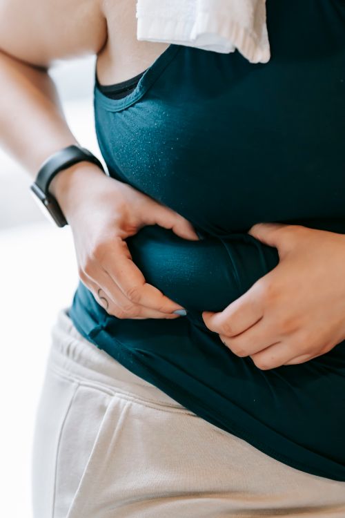 Free Crop faceless plus size female demonstrating problem with overweight by evaluating quantity of excess fat on stomach Stock Photo