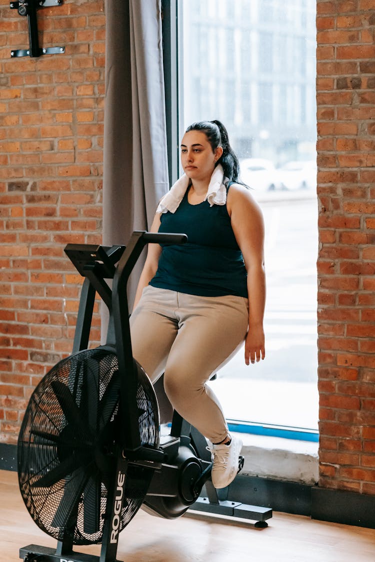 Tired Woman With Hands Down Resting On Cycling Machine