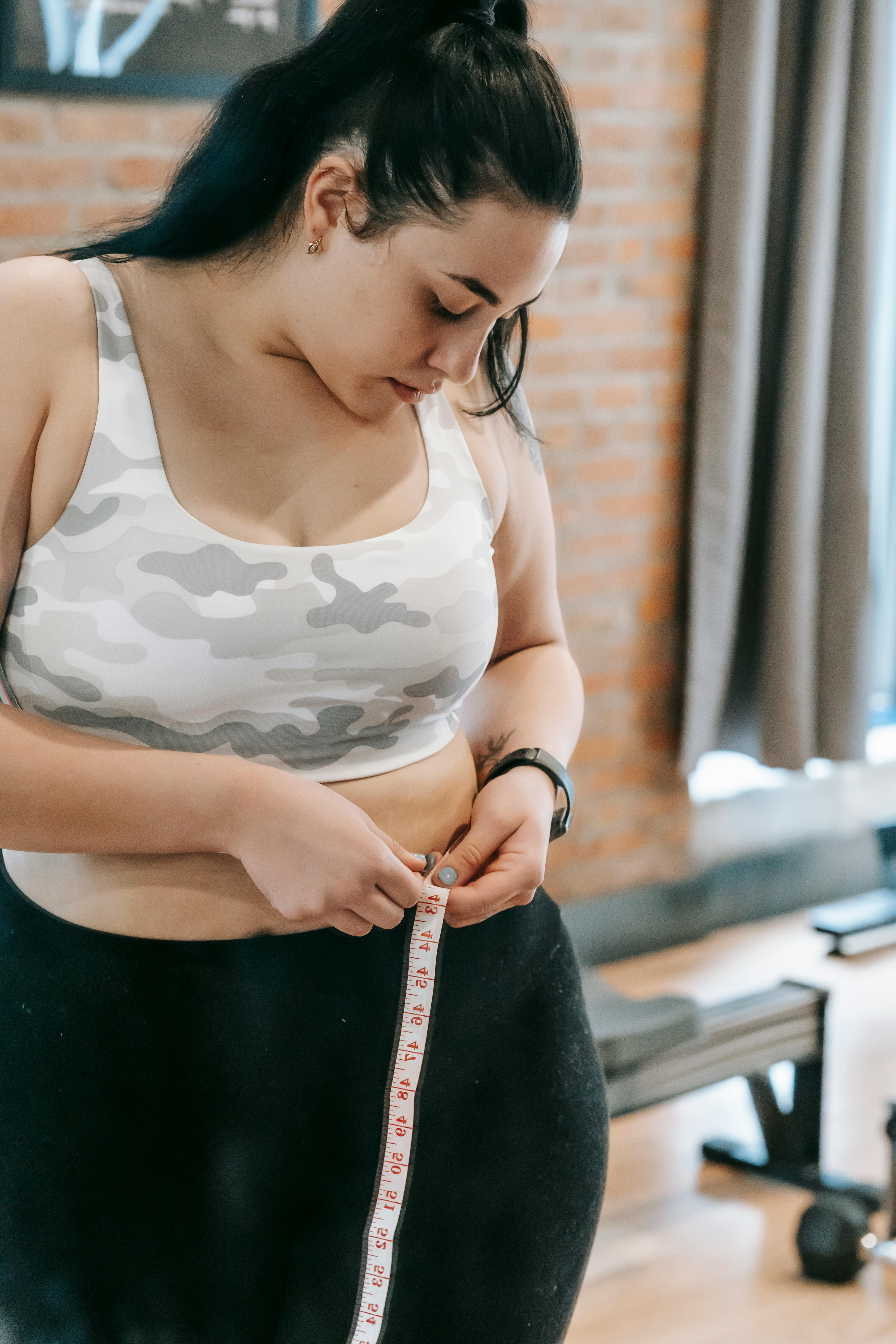 Fitness woman fit girl with measure tape measuring her waist Stock Photo by  ©Voyagerix 45796869