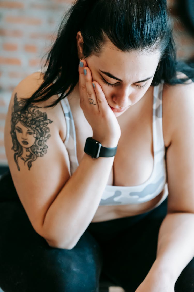 A Concerned Woman Looking Down With Her Hand On Her Cheek