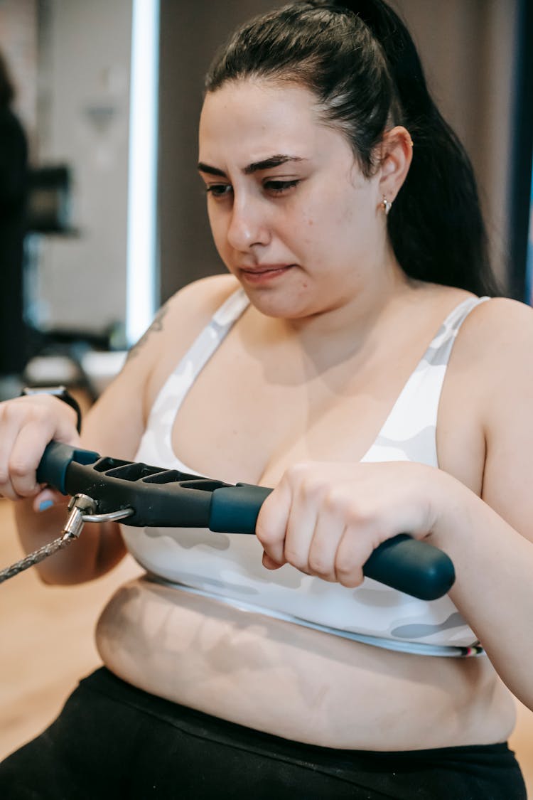 Serious Woman Exercising On Rowing Machine