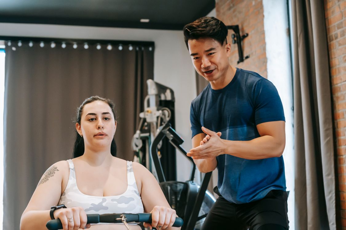 Free A personal trainer assists a woman in effective indoor rowing workout for peak fitness. Stock Photo