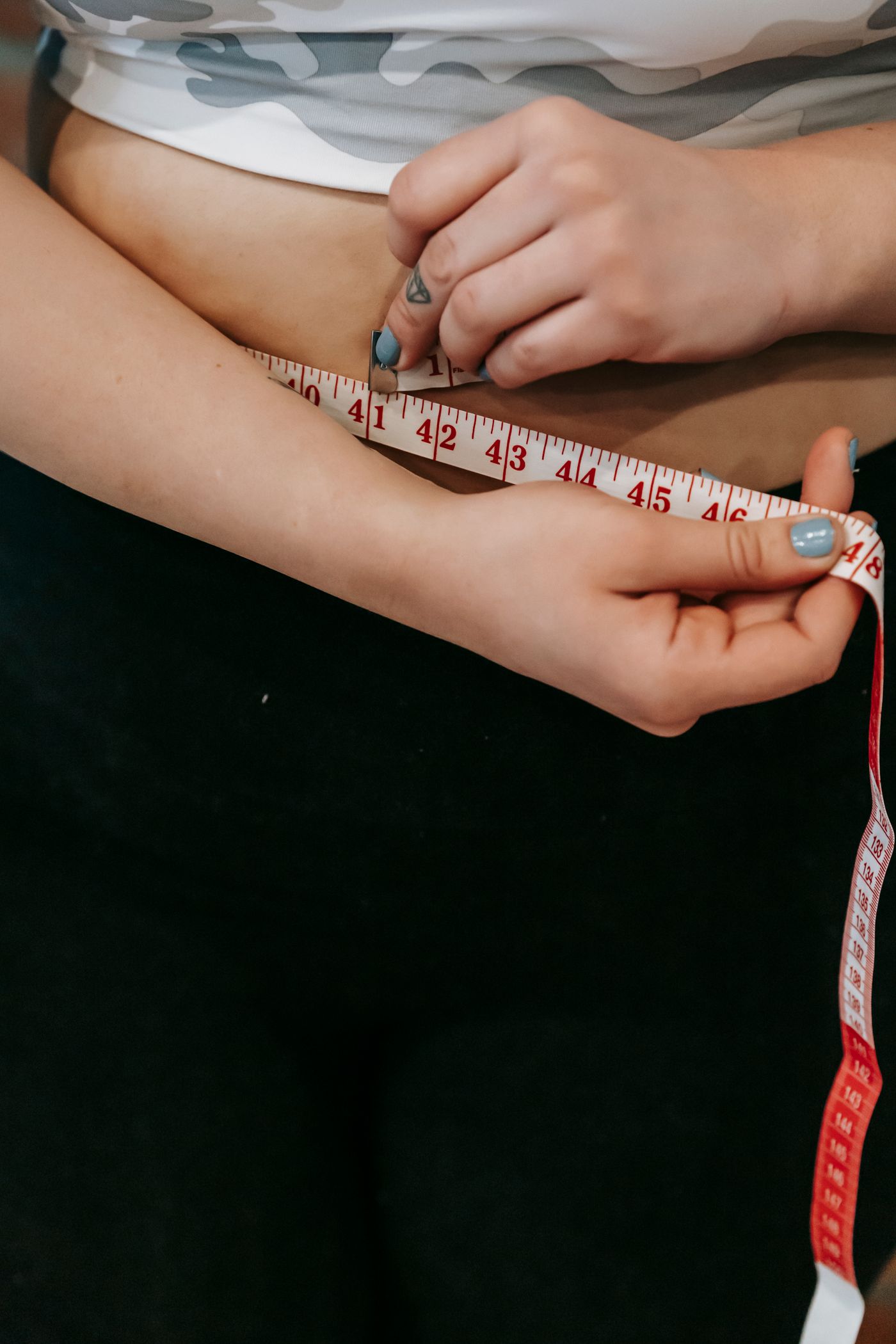 Femme mesurant son tour de taille avec un mètre ruban, suivi du poids après chirurgie bariatrique