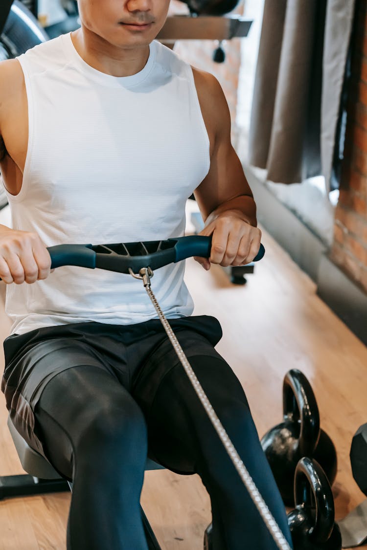 Fit Man Training On Rowing Machine In Gym