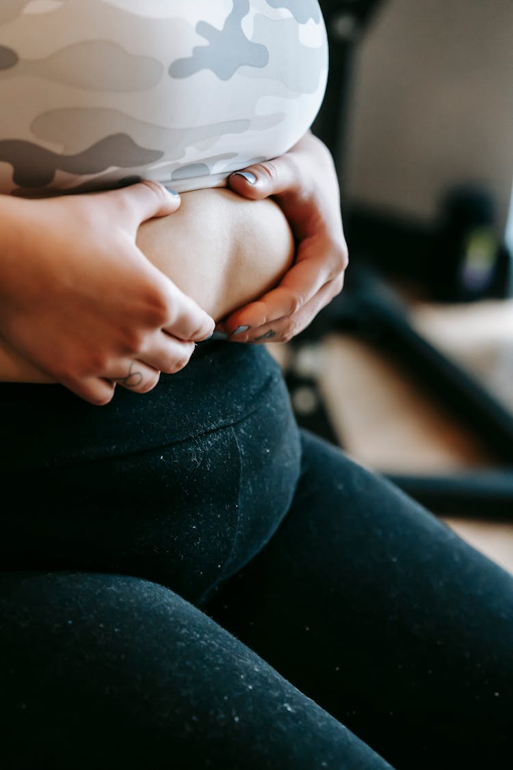 Unrecognizable Plus Size Lady Touching Stomach In Gym