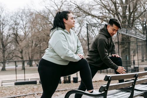 Free Side view of overweight female in sportswear training with Asian sportsman in activewear in park in daylight Stock Photo