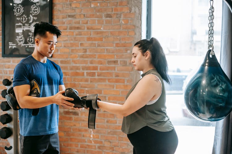 Overweight Female Training With Trainer In Boxing Club