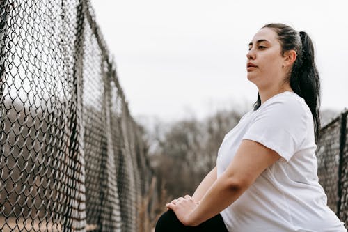 Curvy woman stretching legs near net fence Stock Photo